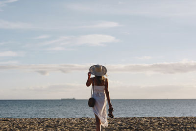 Woman standing at beach against sky