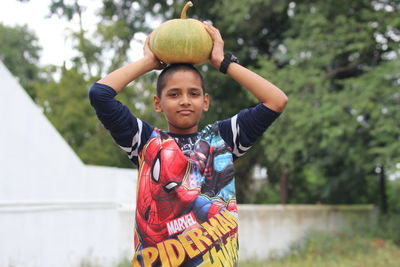 Portrait of boy with arms raised standing outdoors
