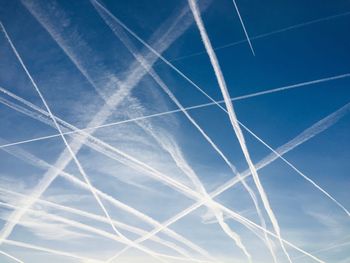 Low angle view of vapor trails in blue sky