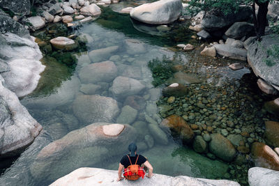 Low section of woman on rock by lake