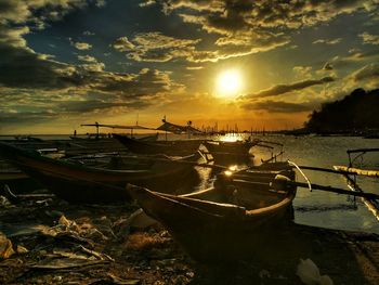 Boats moored on sea against sky during sunset