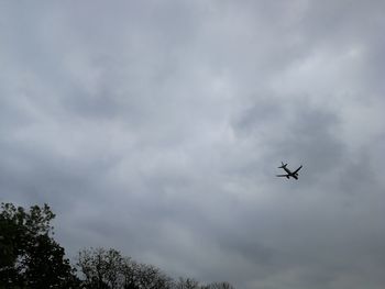 Low angle view of silhouette airplane against sky