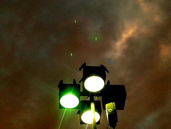 High section of illuminated lamp against cloudy sky