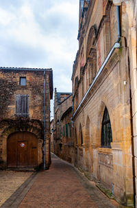 Alley amidst buildings in city against sky