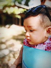 Close-up of cute baby boy looking away while standing outdoors