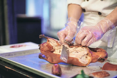 Close-up of chef's hand preparing and cutting peking duck