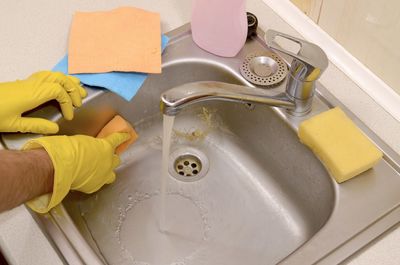 High angle view of man cleaning dirty sink at kitchen