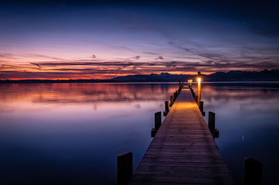 Pier over lake against sky during sunset