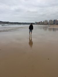 Man walking at beach against sky