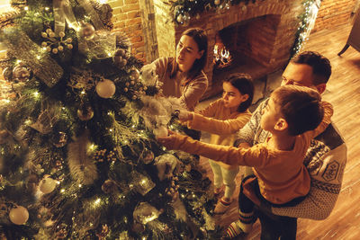 Rear view of woman standing by illuminated christmas tree