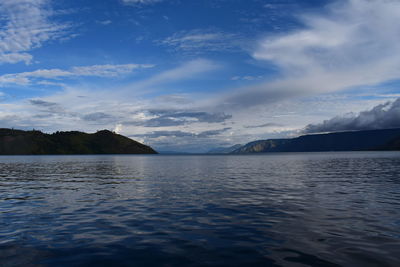 Scenic view of sea and mountains against blue sky