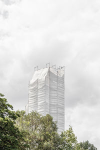 Low angle view of trees and under construction building against sky