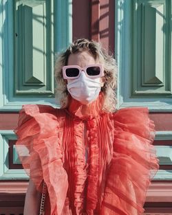 Portrait of woman wearing sunglasses standing by window