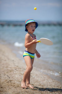 Cute shirtless boy playing at beach during summer