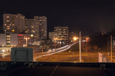 Illuminated street by buildings at night