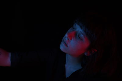 Close-up of sad woman in illuminated darkroom