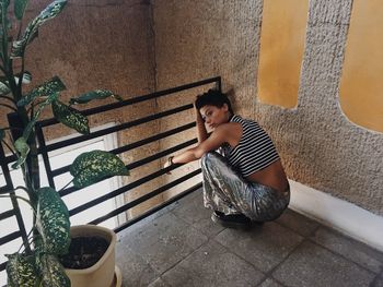 Portrait of boy sitting on potted plant against wall