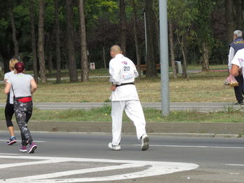 Rear view of man walking on road in city