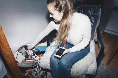 High angle view of woman plugging mobile charger in outlet at dorm room