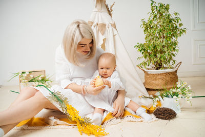 Mother and daughter at home in a white room with flowers tent in the background of spring