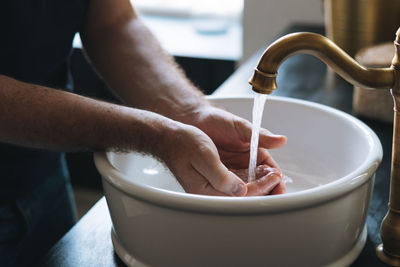 Young man washes his hands in sink in bathroom at home