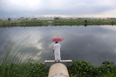 Woman standing by lake against sky