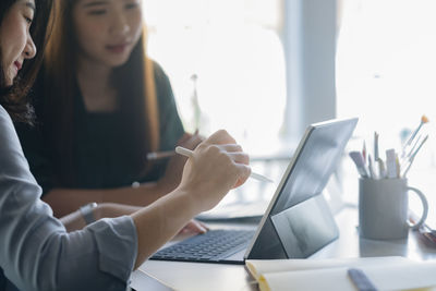 Business females discussing over laptop at desk in office