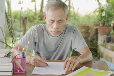 Man holding paper while sitting on table