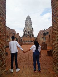 Rear view of man and woman standing against building