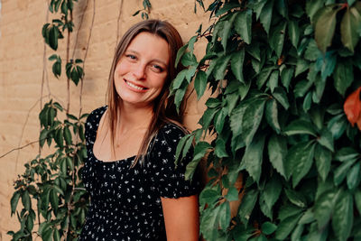 Portrait of young woman standing against plants