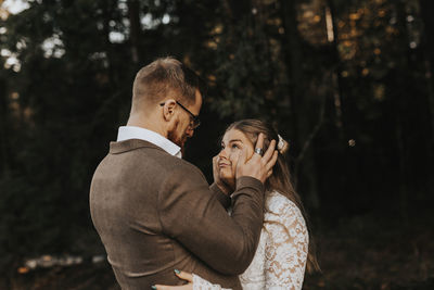 Midsection of couple kissing against trees