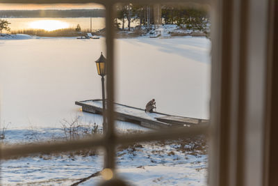 Man on frozen lake against sky during winter