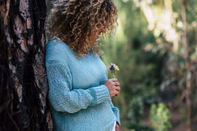 Midsection of woman holding tree trunk