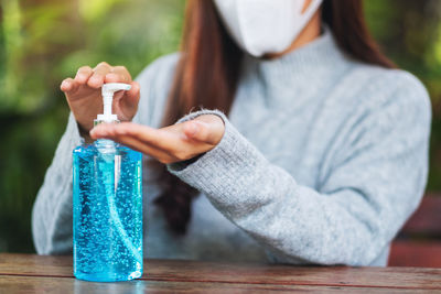 Midsection of woman holding bottle