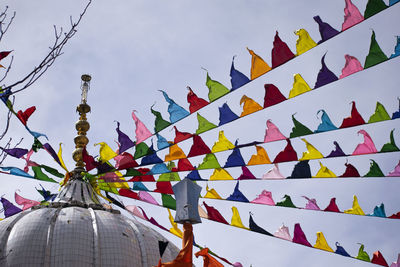 Low angle view of multi colored umbrellas on building against sky