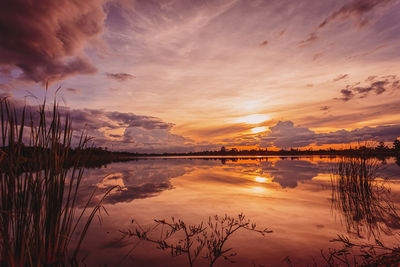 Scenic view of lake against dramatic sky during sunset