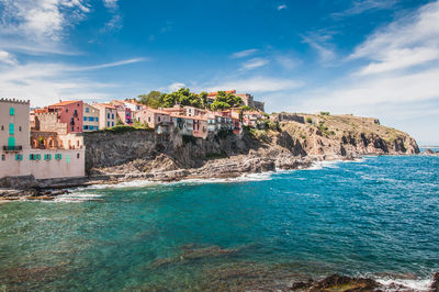 Scenic view of sea by buildings against sky