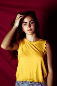 Portrait of beautiful young woman standing against curtain