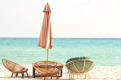 Deck chairs on beach against clear sky