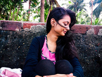 Young woman sitting against retaining wall