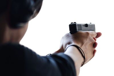 Close-up of woman shooting with handgun against white background