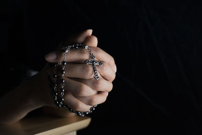 Close-up of woman holding hand over black background