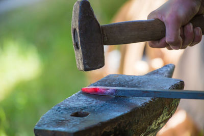 Cropped hand hammering metal on anvil
