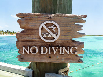 Close-up of information sign on beach against sky