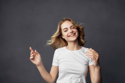 Young woman smiling against black background