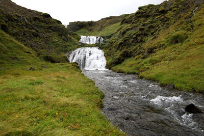 Scenic view of waterfall amidst rocks against sky