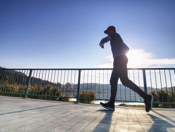 Full length of man on railing against sky during sunset