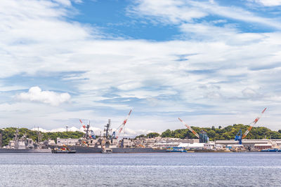 Cranes at harbor against sky