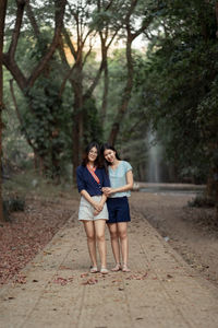 Woman standing on footpath against trees