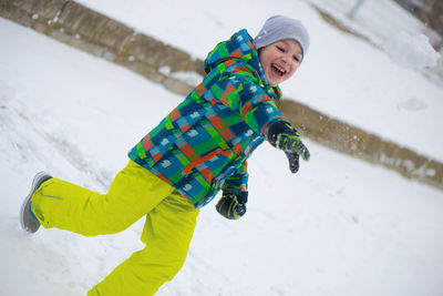 Boy throwing snow while standing in snow outdoors